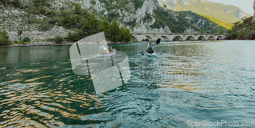 Image of A group of friends enjoying having fun and kayaking while exploring the calm river, surrounding forest and large natural river canyons