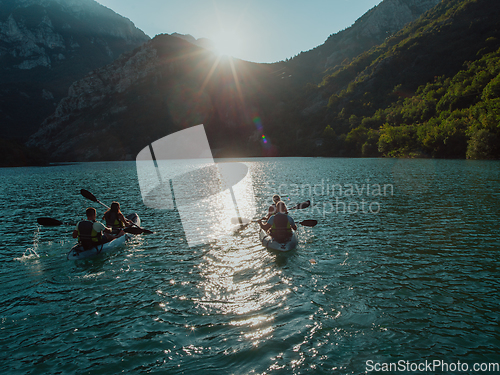 Image of A group of friends enjoying fun and kayaking exploring the calm river, surrounding forest and large natural river canyons during an idyllic sunset.