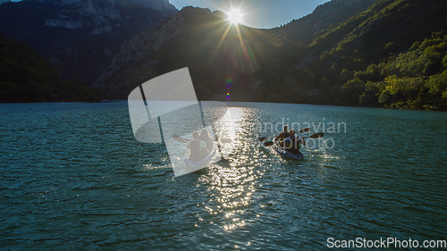 Image of A group of friends enjoying fun and kayaking exploring the calm river, surrounding forest and large natural river canyons during an idyllic sunset.