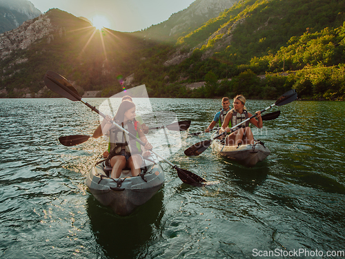 Image of A group of friends enjoying fun and kayaking exploring the calm river, surrounding forest and large natural river canyons during an idyllic sunset.