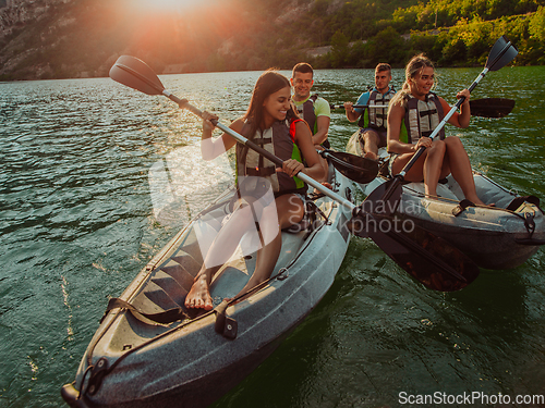 Image of A group of friends enjoying fun and kayaking exploring the calm river, surrounding forest and large natural river canyons during an idyllic sunset.