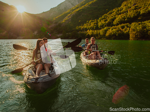 Image of A group of friends enjoying fun and kayaking exploring the calm river, surrounding forest and large natural river canyons during an idyllic sunset.