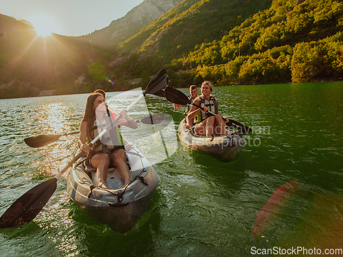 Image of A group of friends enjoying fun and kayaking exploring the calm river, surrounding forest and large natural river canyons during an idyllic sunset.