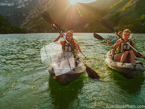 Image of A group of friends enjoying fun and kayaking exploring the calm river, surrounding forest and large natural river canyons during an idyllic sunset.