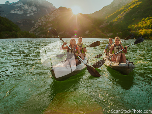 Image of A group of friends enjoying fun and kayaking exploring the calm river, surrounding forest and large natural river canyons during an idyllic sunset.