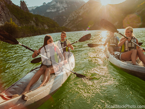 Image of A group of friends enjoying fun and kayaking exploring the calm river, surrounding forest and large natural river canyons during an idyllic sunset.