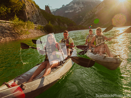 Image of A group of friends enjoying fun and kayaking exploring the calm river, surrounding forest and large natural river canyons during an idyllic sunset.