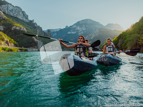 Image of A group of friends enjoying fun and kayaking exploring the calm river, surrounding forest and large natural river canyons during an idyllic sunset.