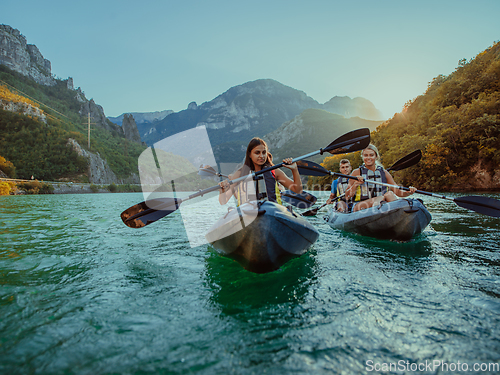 Image of A group of friends enjoying fun and kayaking exploring the calm river, surrounding forest and large natural river canyons during an idyllic sunset.