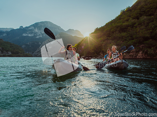 Image of A group of friends enjoying fun and kayaking exploring the calm river, surrounding forest and large natural river canyons during an idyllic sunset.