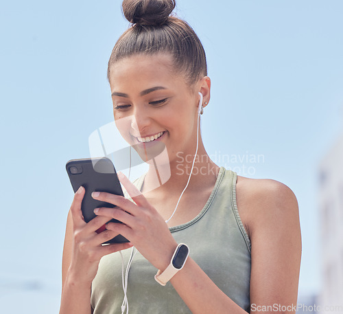 Image of Happy woman, phone and city in fitness, communication or social media smile for outdoor networking. Female person or runner texting or chatting on mobile smartphone app with earphones in urban town