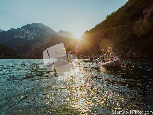 Image of A group of friends enjoying fun and kayaking exploring the calm river, surrounding forest and large natural river canyons during an idyllic sunset.