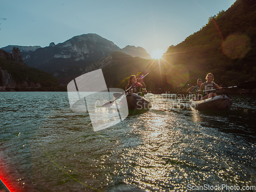 Image of A group of friends enjoying fun and kayaking exploring the calm river, surrounding forest and large natural river canyons during an idyllic sunset.