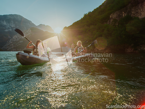 Image of A group of friends enjoying fun and kayaking exploring the calm river, surrounding forest and large natural river canyons during an idyllic sunset.