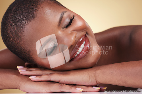 Image of Skin, beauty and makeup of a black woman in studio for self care, glow or cosmetics. Face of African aesthetic model person with facial shine, dermatology and head on hands on beige background