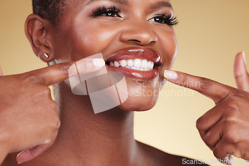 Image of Smile, beauty and a woman pointing at teeth in studio with skin care, glow and makeup. Face of an African model person with dental shine, dermatology and cosmetics announcement on a beige background