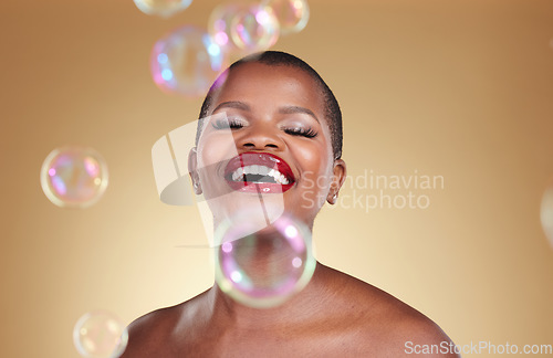 Image of Cosmetics, makeup and bubbles with face of black woman in studio for beauty, spa treatment and luxury. Skincare, dermatology and self care with model on gold background for glow, facial and soap