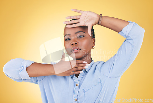 Image of Hands, frame and portrait of African woman in studio for confidence, creativity and beauty. Photography, perspective and face of serious person on yellow background with cosmetics, makeup and glamour