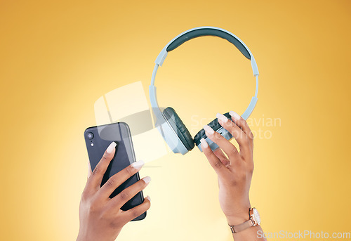 Image of Hands, phone and headphones for music on a yellow background in studio for a streaming subscription service. Mobile, internet and radio with a person listening to audio through an entertainment app