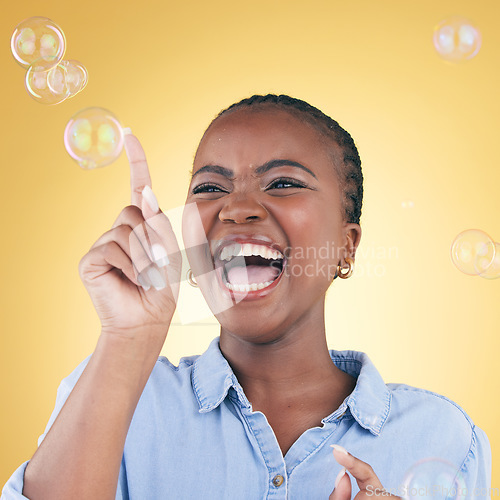 Image of Excited, laugh and black woman on yellow background with bubbles for happiness, joy and have fun. Happy, smile and isolated African person in studio pop soap bubble for playful magic and color