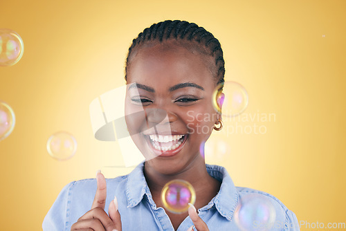 Image of Excited, pop and black woman on yellow background with bubbles for happiness, joy and fun. Playful, smile and isolated happy African person in studio with soap bubble for freedom, magic or color