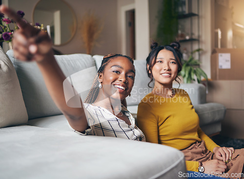 Image of Pointing, friends and women in living room for visit, bonding and conversation in apartment. Hand gesture, showing house decor and black female and Asian person in lounge to relax together on weekend