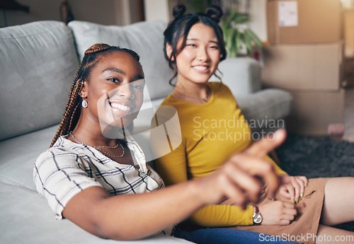Image of Pointing, friends and women in home for visit, bonding and conversation in living room together. Hand gesture, showing house decor and black female and Asian person in lounge to relax on weekend