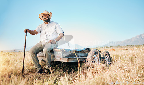 Image of Portrait, African farmer and land in the countryside and man, sitting and watching over agriculture, field and environment. Farming, meadow and happy worker outdoor with happiness or smile in summer