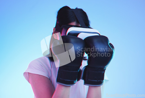 Image of Vr, fitness and woman boxing in esports, video game and fight in studio on blue background with headset technology. 3d, exercise and virtual reality fighting ux or punching with futuristic gaming