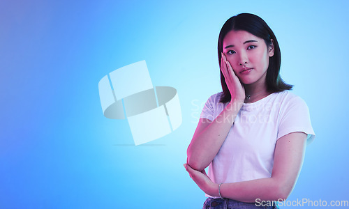 Image of Mockup, neon and portrait of Asian woman in studio for information, promotion and deal on blue background. Creative lighting, marketing and isolated person with space for news, announcement and sale