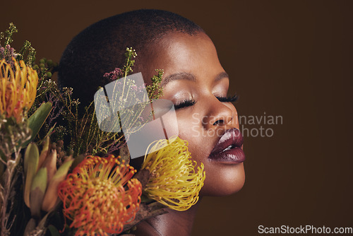 Image of Black woman, flowers and makeup in studio for beauty, wellness or thinking with protea by brown background. Girl, model and glow on facial skin, sustainable cosmetics and eyes closed for aesthetic