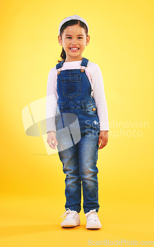 Image of Happy, portrait and girl child for fashion in studio with confidence, smile and positive attitude. Excited, clothes and young kid with happiness, pose and casual style isolated on a yellow background