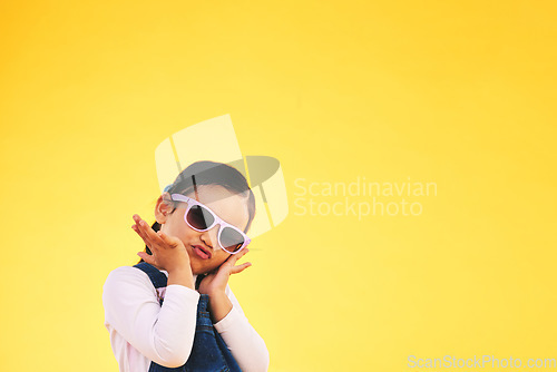 Image of Girl, child and portrait with sunglasses in studio for confidence, cool and fun attitude. Face, space and young kid with mockup, pose and fashion announcement isolated on a yellow background