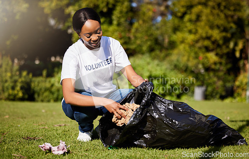 Image of Volunteer, woman and cleaning waste in park for community service, pollution and climate change or earth day project. African person volunteering in garden, nature or outdoor and plastic bag or trash