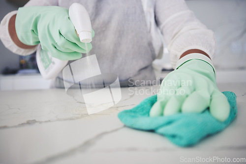 Image of Person, hands and cleaning table with spray bottle, detergent or bacteria or germ removal at home. Closeup of housekeeper, maid or cleaner wiping surface with cloth in clean hygiene or sanitize house