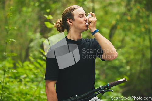 Image of Asthma, fitness and man cyclist on a bicycle in a forest with breathing medical emergency during exercise or training. Outdoor, lung support and athlete with inhaler in nature for workout or wellness