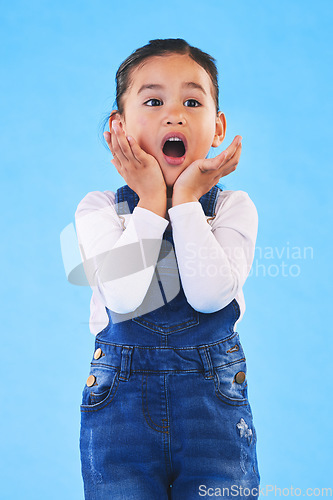 Image of Shocked, wow and girl with hands to face in studio with fear and scared from danger. Alarm, blue background and young child from Hawaii with scary, omg surprise and emoji face of a kid in danger