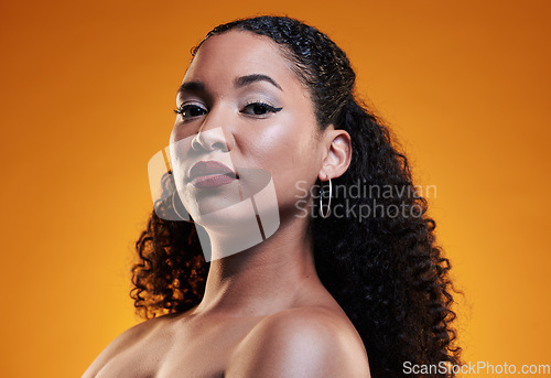 Image of Beauty, curly hair and makeup with portrait of woman in studio for texture, health and cosmetics. Self care, salon and hairstyle with model on orange background for skincare, spa treatment and mockup