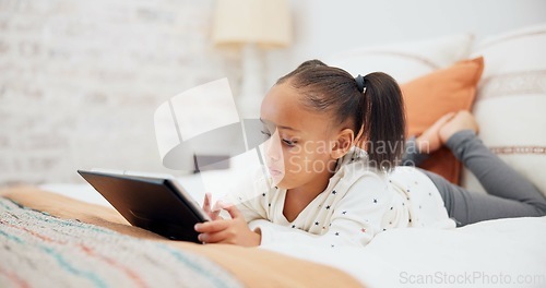 Image of Digital tablet, relax and child on the bed playing an online game or watching a video on the internet. Technology, rest and young girl kid networking on social media or mobile app in bedroom at home.