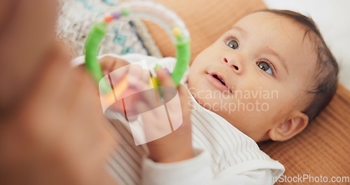 Image of Sweet, playing and cute baby with a toy on a blanket for child development, fun and entertainment. Happy, adorable and playful infant child relaxing on a bed in his nursery or bedroom at family home.