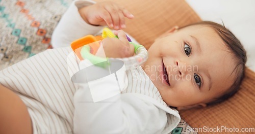 Image of Cute, playing and sweet baby with a toy on a blanket for child development, fun and entertainment. Happy, sweet and portrait of a playful infant child relaxing on a bed in his nursery or bedroom.