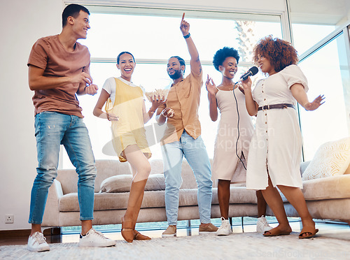 Image of Singing, entertainment and friends dancing in living room with a microphone to music, playlist or radio. Happy, diversity and young people moving, bonding and having fun together with karaoke at home