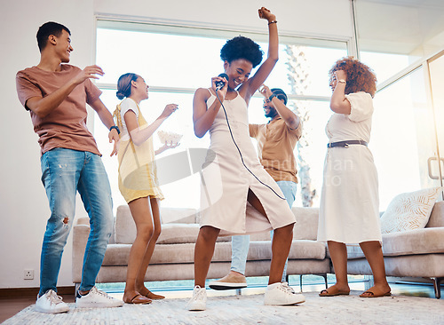 Image of Happy, party and people singing karaoke in the living room with a microphone to music, playlist or radio. Entertainment, diversity and young friends dancing, bonding and having fun together at home.