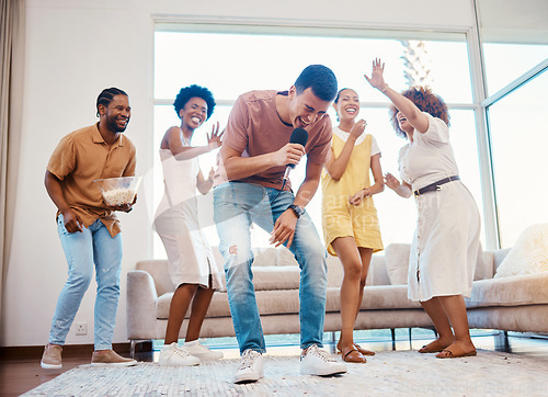 Image of Singing, party and friends dancing in the living room with a microphone to music, playlist or radio. Happy, diversity and young people moving, bonding and having fun together with karaoke at home.