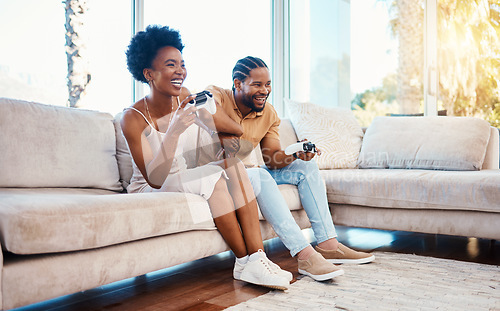 Image of Gaming, funny and a black couple on a sofa in the living room of their home together for bonding. Love, fun or leisure with a gamer man and woman playing online using a console in their house