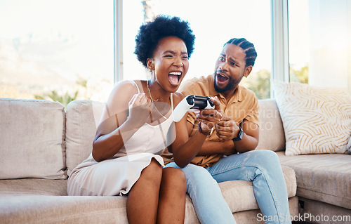 Image of Gaming, winner and a black couple on a sofa in the living room of their home together for bonding. Love, fun or competition with a gamer man and woman playing online using a console in their house