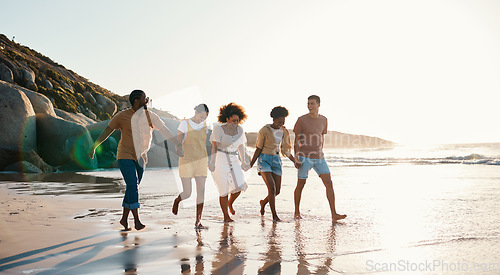 Image of Summer, friends and people happy at sunset beach for fun, holding hands and travel with love. Diversity, men and women group in nature with sand, freedom and happiness on a vacation or holiday
