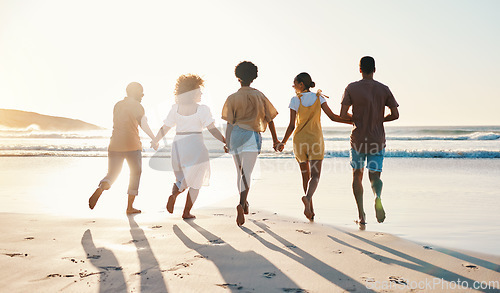 Image of Friends, holding hands and running at sunset on beach in summer, vacation or walking together on holiday break with freedom. Group, silhouette and people with connection and support in community