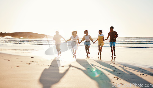 Image of Friends, holding hands and running at sunset on beach in summer or walking together on holiday in California with freedom. Group, silhouette or vacation with connection or support in community