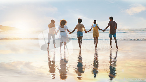 Image of Friends, together and holding hands on beach at sunset in summer, vacation or walking on holiday break with support. Group, silhouette and people with connection, respect and kindness in community